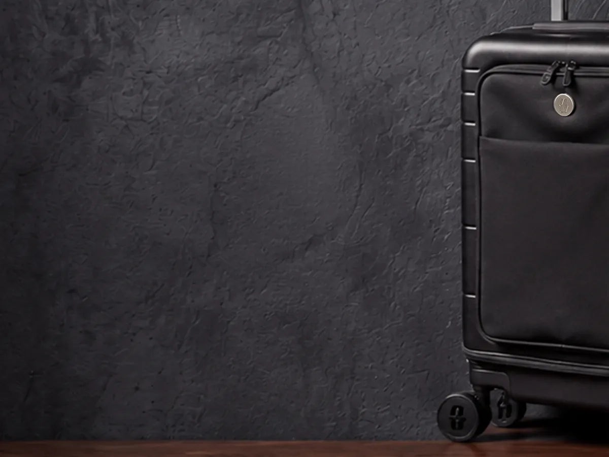 The Vasy carry-on in midnight black on the dark studio set.