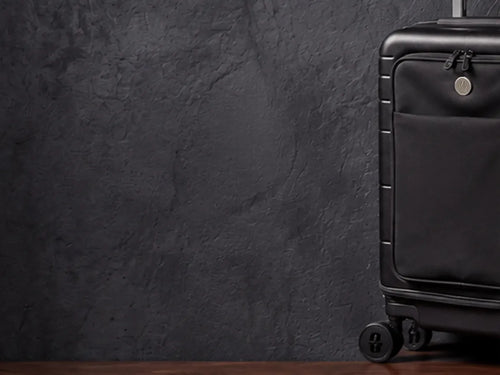 The Vasy carry-on in midnight black on the dark studio set.